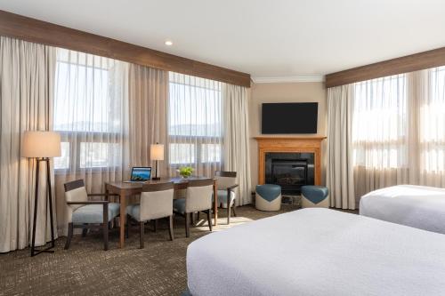 a hotel room with a desk and a room with two beds at Best Western Plus Waterbury - Stowe in Waterbury