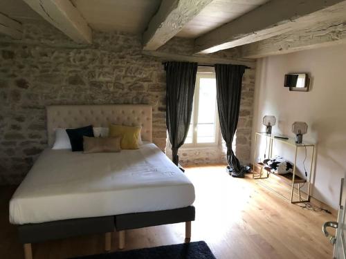 a bedroom with a large bed with a stone wall at Domaine des Annouillards in Sornac