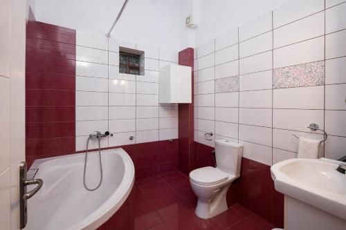 a bathroom with a tub and a toilet and a sink at Callistemon Loft Apartment in Potos