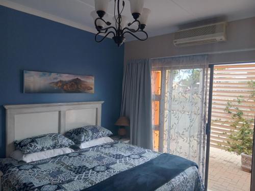 a blue bedroom with a bed and a window at SONHOS dreams Self catering apartment Unit 1 in Bloemfontein