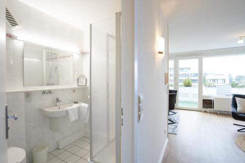 ein weißes Bad mit einem Waschbecken und einem WC in der Unterkunft TER 315 - Terrassenhuegel - Seeblick in Scharbeutz