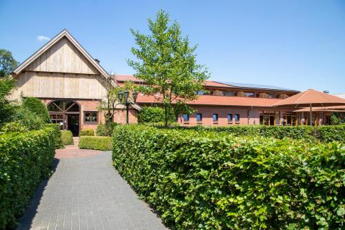 a building with a brick walkway in front of a hedge at Landhuus Laurenz in Am Berge
