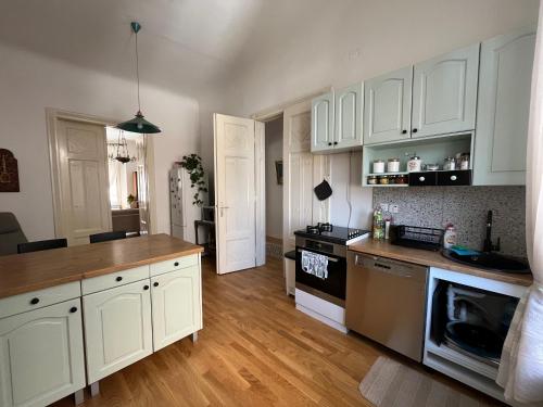 a kitchen with white cabinets and a wooden floor at The Best Location salon apartment with main street view in Sarajevo