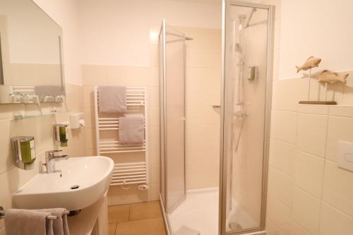 a white bathroom with a shower and a sink at Hotel Das kleine Glück - Adults Only in Sankt Peter-Ording