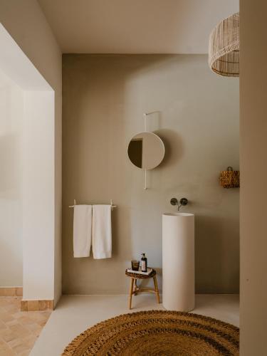 a bathroom with white towels and a table and a mirror at Amagatay Luxury Boutique Hotel - Adults Only in Alaior