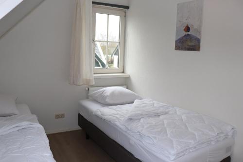 1 dormitorio con 2 camas y ventana en Vakantievilla Hunzedrôme 82 Drenthe, en Gasselternijveen