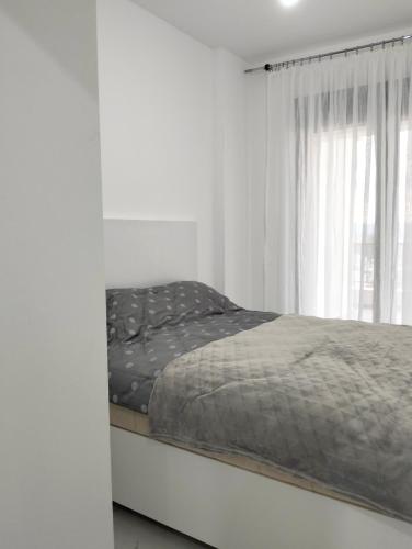 Cama en habitación blanca con ventana en Tivat Apartman, en Tivat