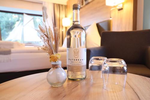 a bottle of wine and two glasses on a table at Hotel Das kleine Glück - Adults Only in Sankt Peter-Ording
