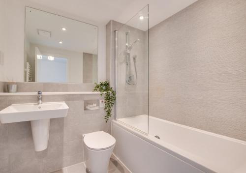 a bathroom with a sink and a toilet and a bath tub at Shearwaters in Seaton