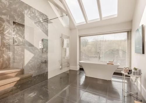 a bathroom with a white tub and a window at The Barn at Lower Longcombe in Stoke Gabriel
