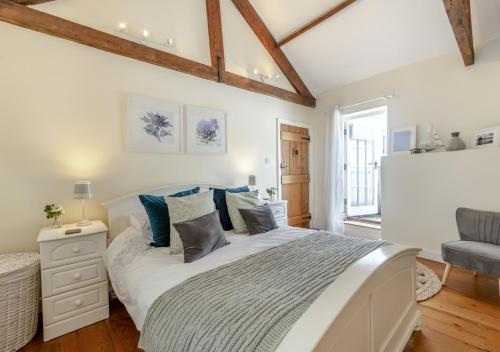 um quarto com uma grande cama branca com almofadas azuis em Ferrymans Cottage em Appledore