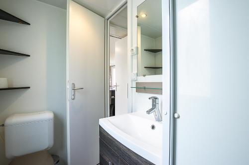 a bathroom with a toilet and a sink and a mirror at Mobilhome tout confort in Saint-Jean-de-Monts