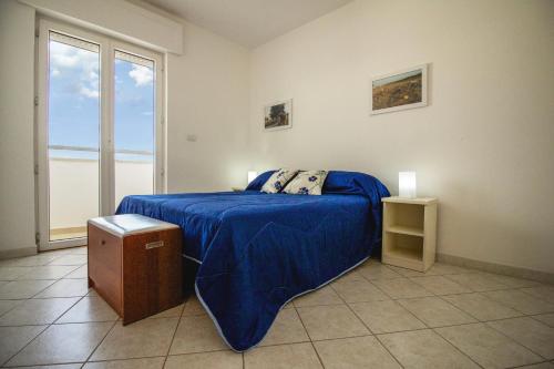 ウジェントにあるLa Ginestra Residenceのベッドルーム1室(青い毛布、窓付)