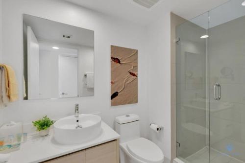 a white bathroom with a sink and a shower at To Steps from the Beach - Coastal Bliss, Pool- Gym in Hallandale Beach