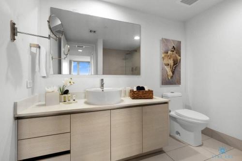 a bathroom with a sink and a toilet and a mirror at Condo Retreat with Stunning Views and Amazing Pools in Hallandale Beach