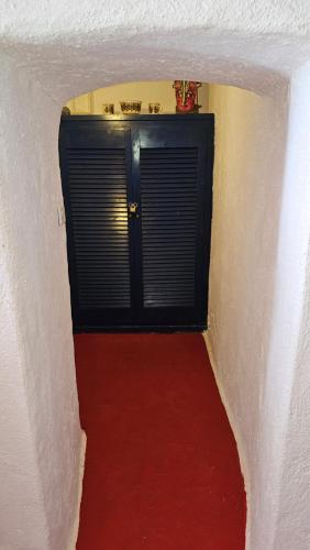 a hallway with a black door and a red carpet at Cactus cave house on the caldera in Firostefani