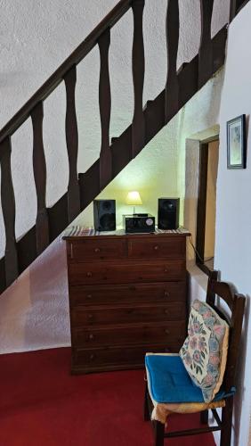 a room with a dresser and a staircase with a blue chair at Cactus cave house on the caldera in Firostefani
