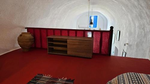 a room with a red floor and a table in a room at Cactus cave house on the caldera in Firostefani