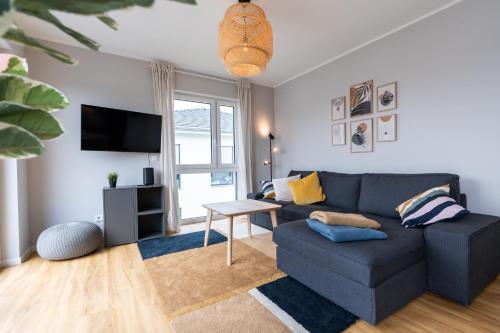 een woonkamer met een blauwe bank en een tv bij Moderne & Familienfreundliche Ferienwohnung am Goitzschesee in Pouch