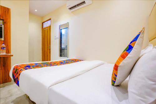 um quarto com uma cama branca e uma almofada colorida em FabExpress Emirates Suits em Mumbai