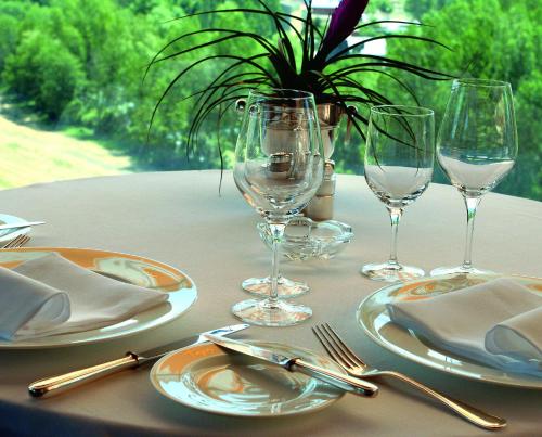 a table with plates and wine glasses on it at HOTEL & SPA El Castell de Ciutat in La Seu d'Urgell
