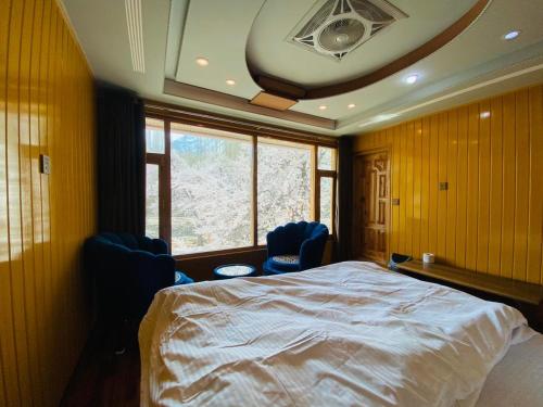 a bedroom with a large bed and two blue chairs at North Palace Khaplu in Khaplu