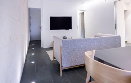 Ampersand - Bright 2-Bedroom Apartment في برشلونة: غرفة معيشة مع أريكة وتلفزيون على الحائط
