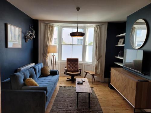 a living room with a blue couch and a television at George St Townhouse in Leamington Spa