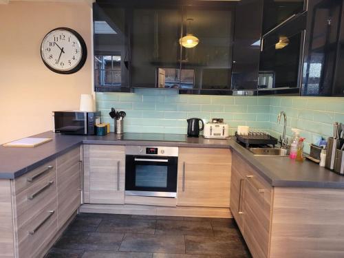 a kitchen with wooden cabinets and a clock on the wall at George St Townhouse in Leamington Spa