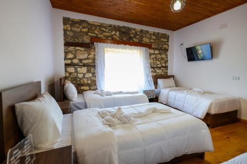 um quarto com três camas e uma janela em Villa Shpiragu Village Experience em Berat