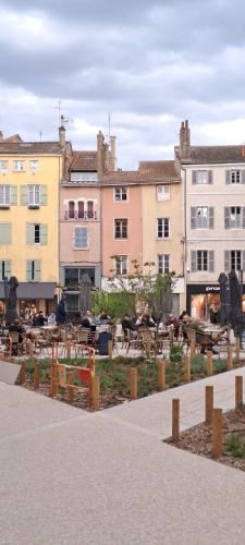 un groupe de bâtiments avec des tables devant eux dans l'établissement Studio centre Macon place aux herbes, à Mâcon