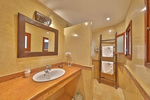 a bathroom with a sink and a mirror and a tub at Riad Dar L'Oussia & SPA in Essaouira