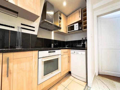 - une cuisine avec des placards en bois et des appareils blancs dans l'établissement Apartment Colisee, à Paris