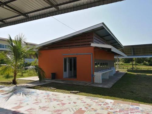 a small orange building with a palm tree in front of it at FriendTogether Armthong in Ban Khlong Kathon