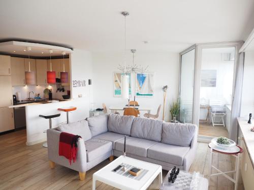 ein Wohnzimmer mit einem Sofa und einer Küche in der Unterkunft Ferienwohnung Schleiverliebt 19-8 im Wikingturm Schleswig in Schleswig