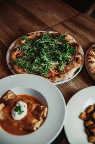 a table with two plates of food and a pizza at Hotel La Riva in Siófok