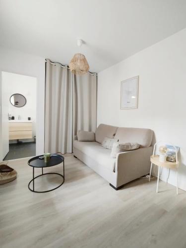 un salon blanc avec un canapé et une table dans l'établissement Stylish Cocoon: studio tout confort au cœur de Pau, à Pau