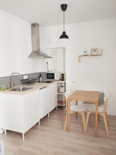 une cuisine avec des armoires blanches et une table en bois dans l'établissement Stylish Cocoon: studio tout confort au cœur de Pau, à Pau