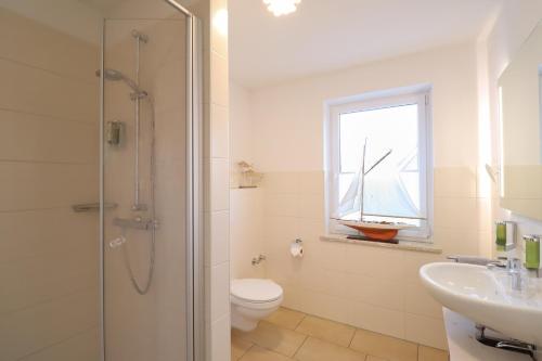 a bathroom with a shower and a toilet and a sink at Hotel Das kleine Glück - Adults Only in Sankt Peter-Ording