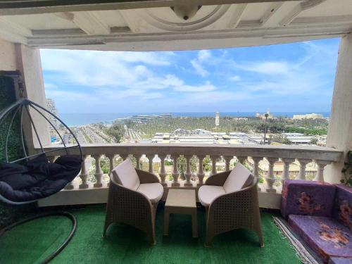 Sea and Montaza Palace view 2 bedrooms apartment alexandria,2 full bathrooms, with 2 AC and 1 Stand Fan, wifi, 4 blankets available في الإسكندرية: بلكونه مع طاوله وكراسي واطلاله