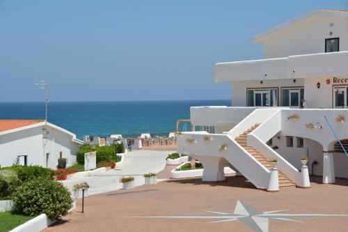 een wit gebouw met een trap naast de oceaan bij Residence Cala del Mar - Happy Rentals in Marina di Sorso