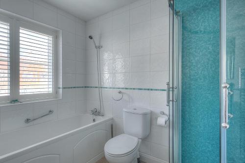 a bathroom with a toilet and a tub and a shower at 2 Studley Gardens in Lyme Regis