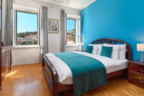 a blue bedroom with a bed and two windows at Sun Spalato Fara in Hvar