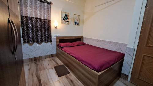 ein kleines Bett in einem Zimmer mit einer roten Decke in der Unterkunft Laxmi Niwas, Salt Lake, Kolkata, 10mins from Sector 5 in Kalkutta