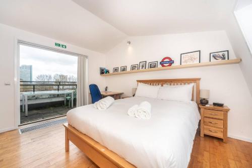 um quarto com uma cama branca e uma grande janela em Pass the Keys - Sunny flat with Great views over Canary Wharf, London em Londres