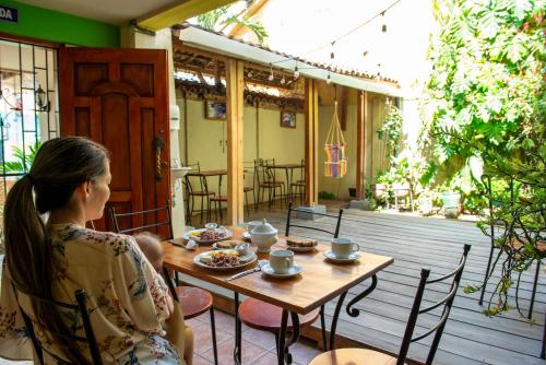 een vrouw aan een tafel op een patio bij Hostal La Buena Onda in Matagalpa