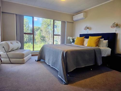 Un dormitorio con una cama con almohadas amarillas y una silla en The waterfront 361-Family retreat with Netflix Skysport Air conditioner in each bedroom en Auckland