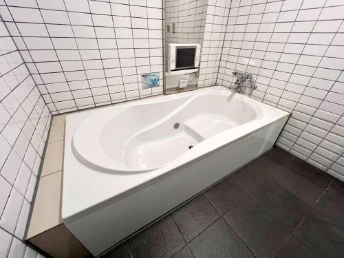 a white bath tub in a white tiled bathroom at もしもしピエロ NEO 京都店 in Kyoto