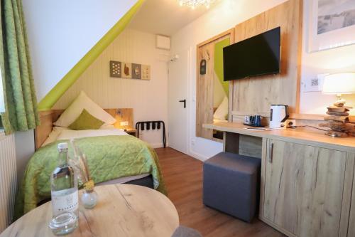 a bedroom with a bed and a table with a bottle of wine at Hotel Das kleine Glück - Adults Only in Sankt Peter-Ording