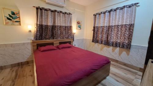 a bedroom with a red bed with two windows at Laxmi Niwas, Salt Lake, Kolkata, 10mins from Sector 5 in Kolkata